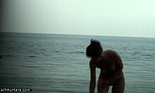Karcsú csaj teljesen meztelen testét mutatja egy nudista strandon
