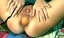Versaute Schlampe schiebt sich eine riesige orangefarbene Kugel in ihr Arschloch